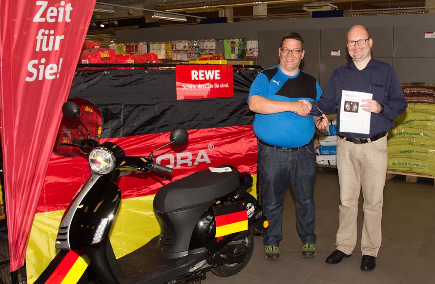 Torsten Nieuwenhuis (links) erhält von Marktleiter Achim Lütfring seinen neuen Motorroller